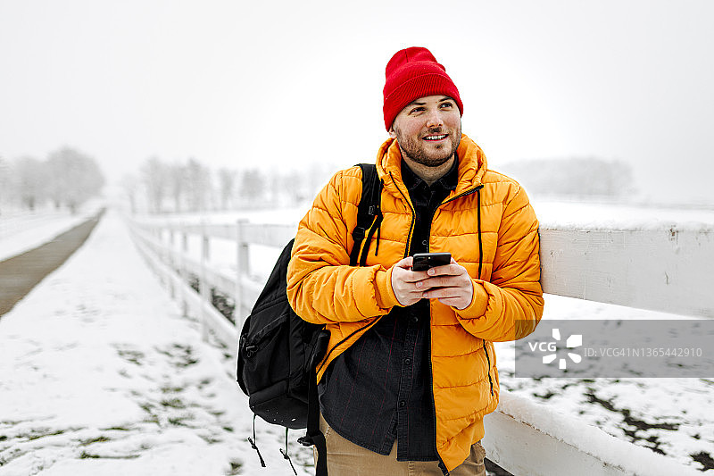 一名年轻人在下雪天在大自然中使用智能手机图片素材