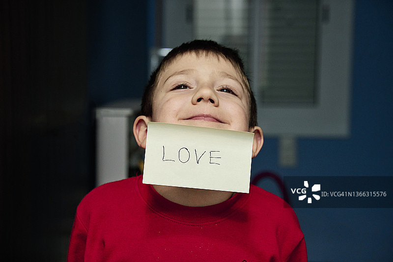 小男孩脸上贴着写着"爱"的便条图片素材