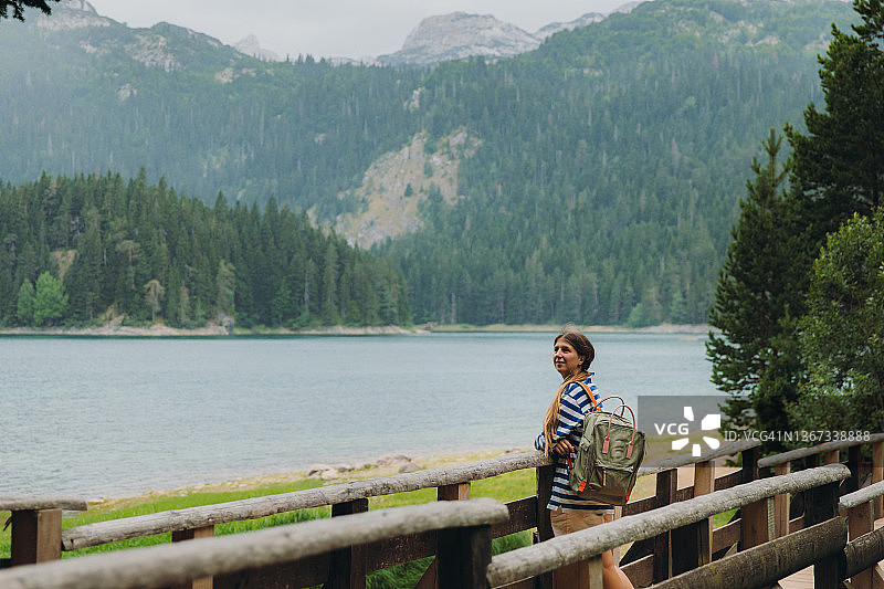 女游客在夏雨中探索风景秀丽的山湖图片素材