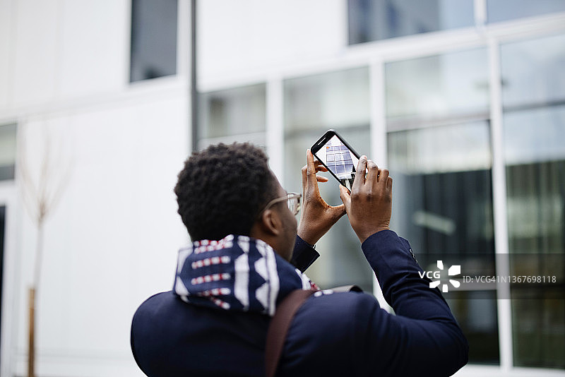 一个年轻的城市商人用手机拍照图片素材