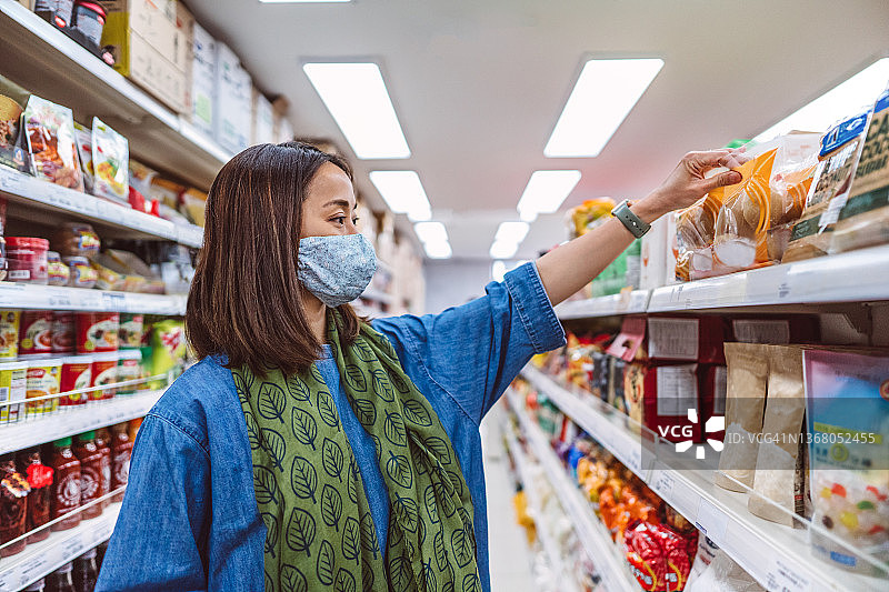 年轻的亚洲妇女带着防护口罩在超市购物图片素材