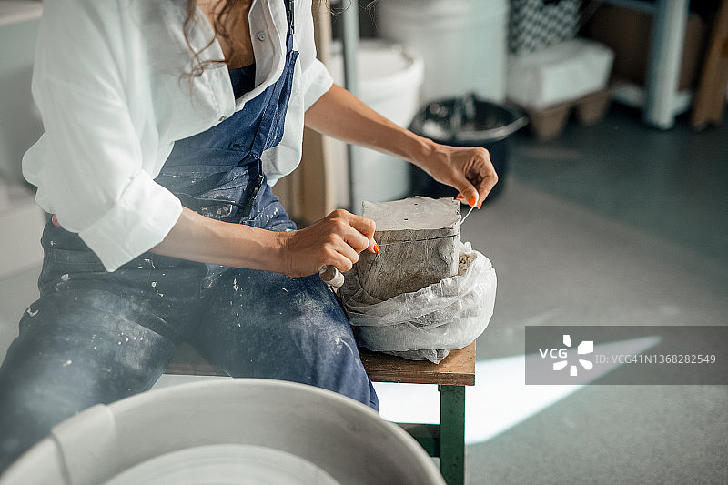 无法辨认的女人，在艺术工作室的陶轮上制作陶器。图片素材