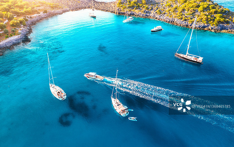 从空中俯瞰夏日日落时海上美丽的游艇和船只。土耳其的Akvaryum koyu。俯瞰豪华游艇，帆船，清澈的蓝色的水，岩石，泻湖，海岸，绿色的树木。旅行图片素材