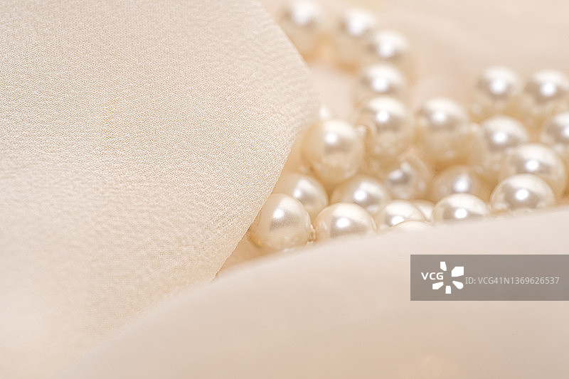 珍珠首饰和精致的米色薄纱织物，微距镜头。图片素材