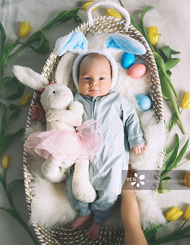 可爱的复活节小兔子。小男孩长着兔子耳朵，复活节彩蛋装在柳条筐里，里面有白色的皮毛。象征复活节假期，出生，春天，宗教。图片素材