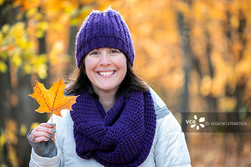 加拿大魁北克，一名女子在森林里徒步采摘秋叶图片素材