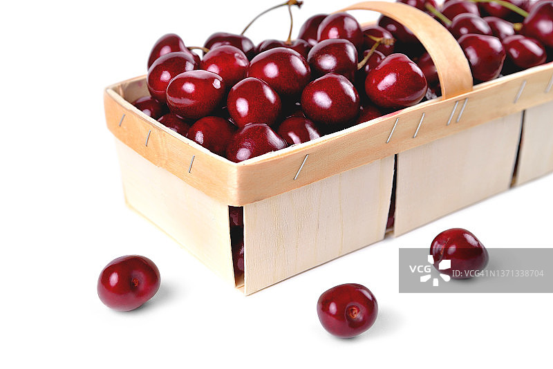 樱桃在一个篮子，成熟的红色樱桃在一个柳条篮子在白色的背景，特写镜头图片素材