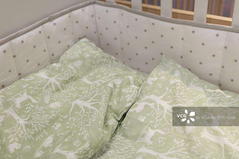 有绿色被子的婴儿床图片素材