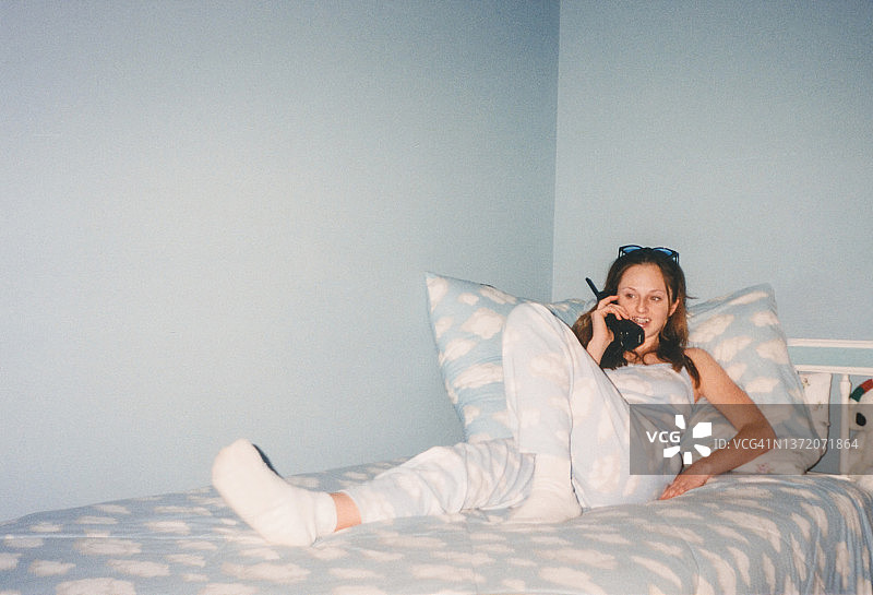 20世纪90年代的复古少女在电话里聊天卧室云印花Y2K 2000年的时尚图片素材