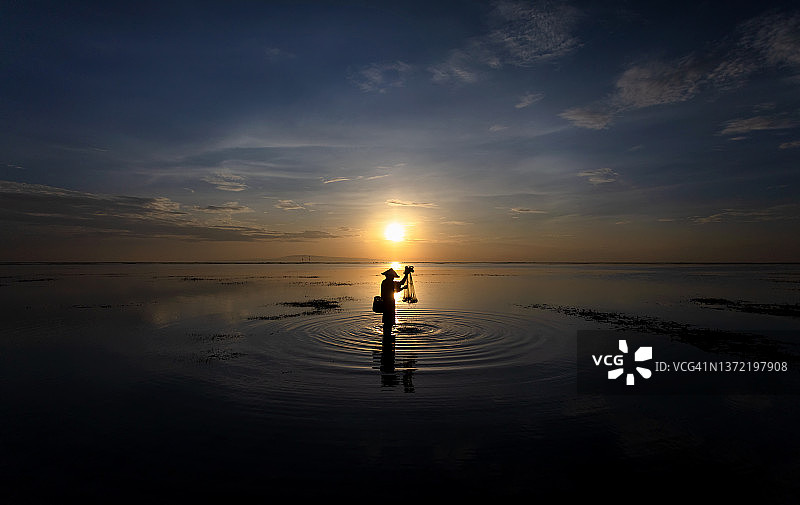 轮廓巴厘男性垂钓印度尼西亚海岸日出图片素材