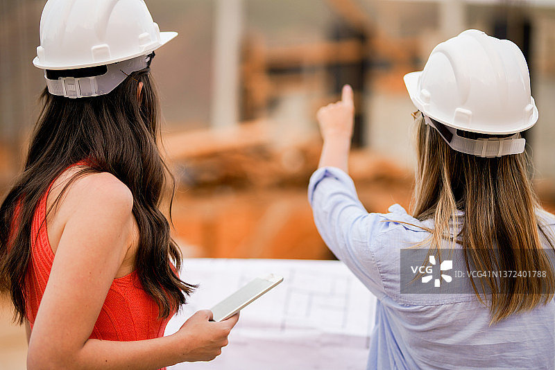 两名女工程师在建筑工地检查时使用图纸图片素材