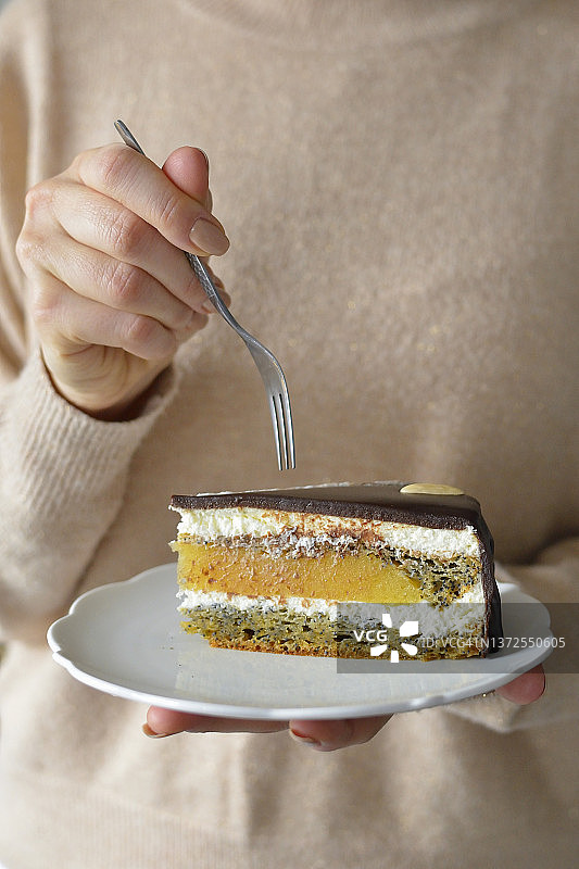 女人手里拿着一个盘子，里面装着蛋糕，蛋糕上有橘子果冻和巧克力图片素材