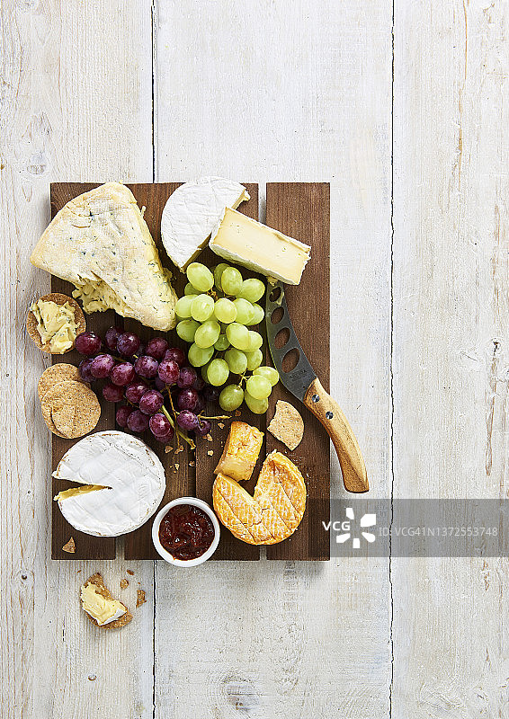 在棕色木板上选择软奶酪、饼干、葡萄和酸辣酱图片素材