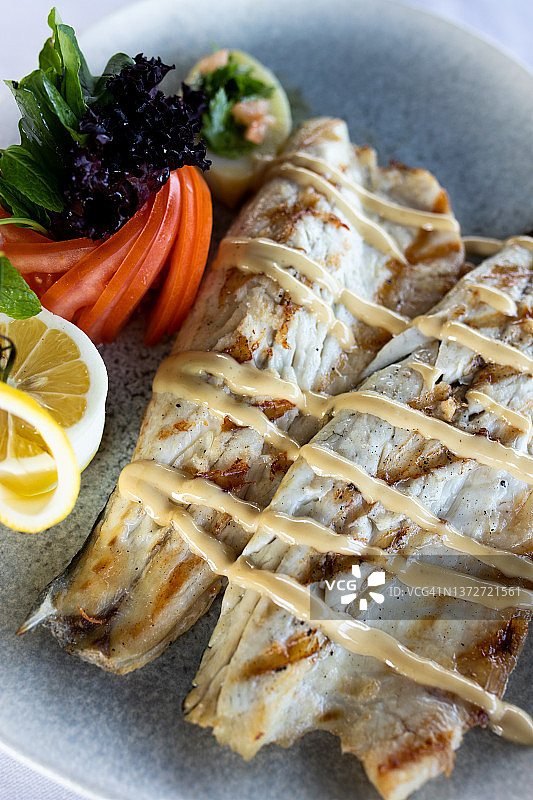 白色盘子上烤海鲈鱼配番茄和柠檬图片素材