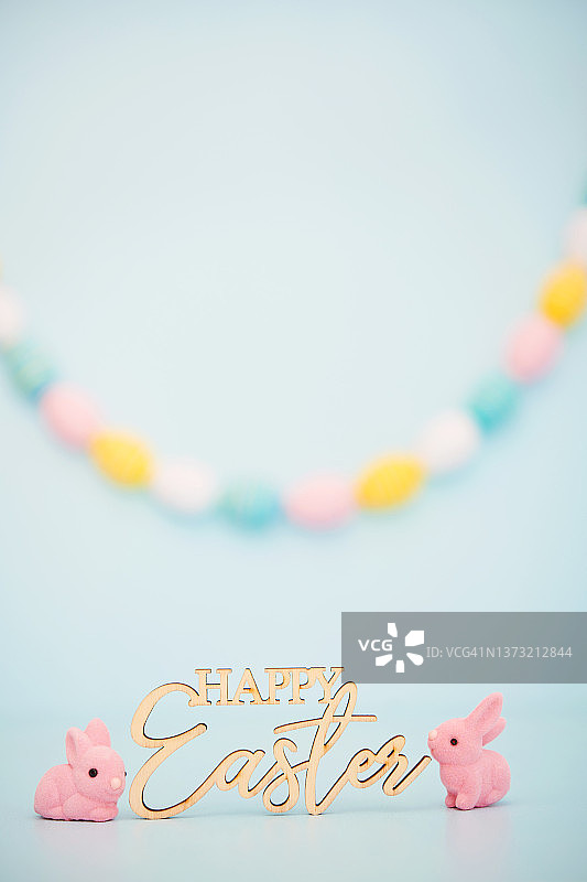 复活节快乐的标志在脚本与两个粉红色的复活节兔子和复活节花环在背景中图片素材