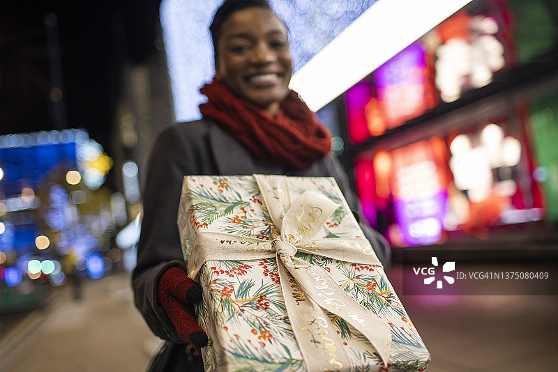 肖像快乐的年轻女子与圣诞礼物在城市街道的夜晚图片素材