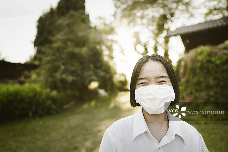 近距离肖像亚洲女性展示如何在COVID-19大流行期间戴双重口罩的安全户外生活方式图片素材