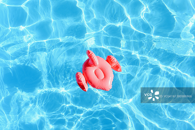 在水池中以粉红色火烈鸟的形式游泳。游泳池。暑假。休息。蓝色的水。在游泳池里游泳。假期。炎热的天气。粉红色的火烈鸟。游泳。游泳圈。图片素材