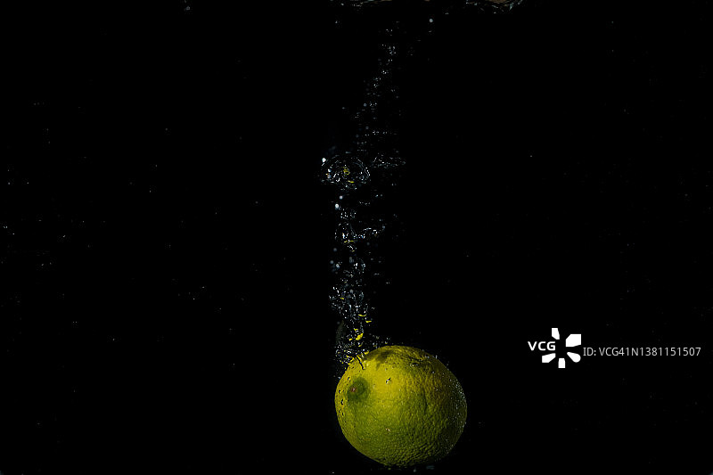 新鲜的水果落在水与溅在黑色的背景。图片素材