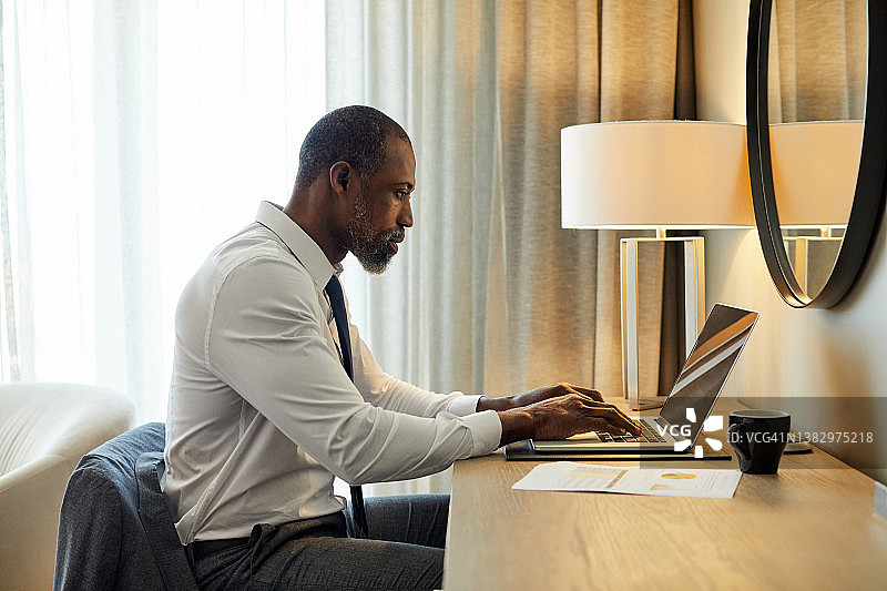 企业家在酒店的桌子上用笔记本电脑工作图片素材