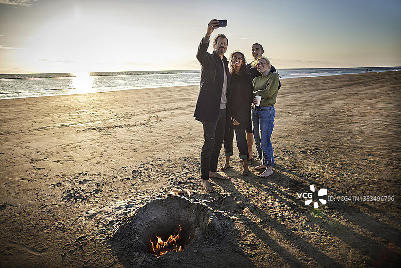 快乐的朋友在日落时在海滩上自拍图片素材