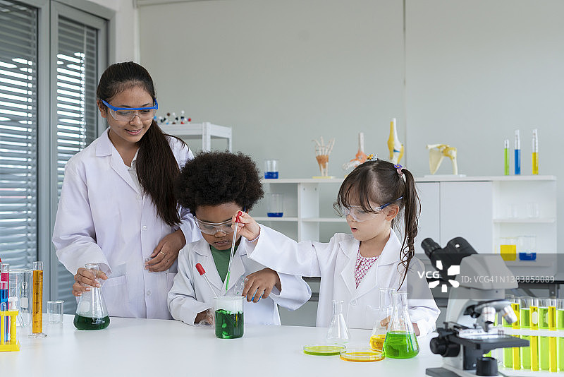在小学科学教室里，兴奋的女孩们一起使用化学图片素材