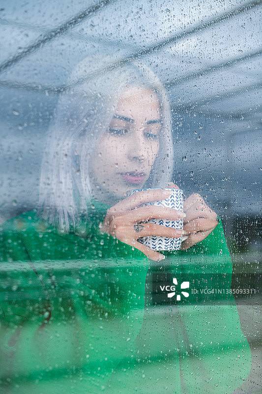 沮丧的女人透过窗户看雨图片素材