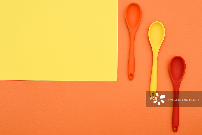 橙色背景的彩色硅胶勺。烹饪的背景。烹饪弗拉。美食博客。餐具。图片素材