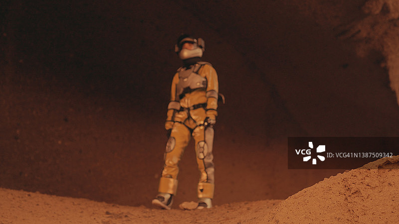 火星漫步。女宇航员探索生锈的山脉。爬上岩石图片素材