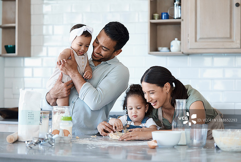 一个女人和她的丈夫和两个女儿在厨房里烤面包图片素材