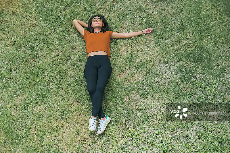 亚洲女人躺在绿草地上图片素材