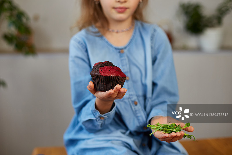 小女孩比较食物，选择甜蛋糕反对微绿色不健康的习惯图片素材