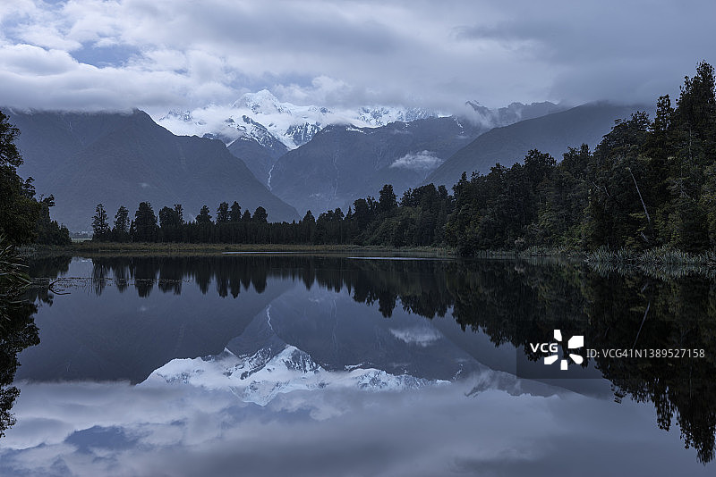 马西森湖、库克山和塔斯曼山在云雾中倒映在水中。这个湖被温带雨林环绕着。新西兰西海岸地区。联合国教科文组织世界遗产。图片素材