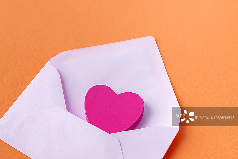 打开的粉红色信封，里面有一个橙色背景的爱的信息图片素材
