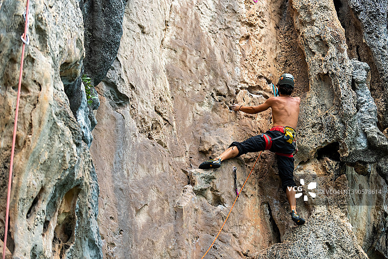 亚洲年轻人在热带岛屿的岩石山上爬山度假图片素材