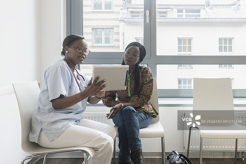女医生在候诊室用数码平板电脑与病人交谈图片素材