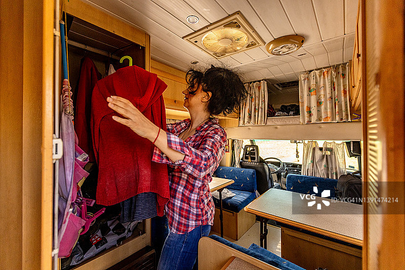 中年妇女，整理她的衣服在衣柜里，在露营车图片素材