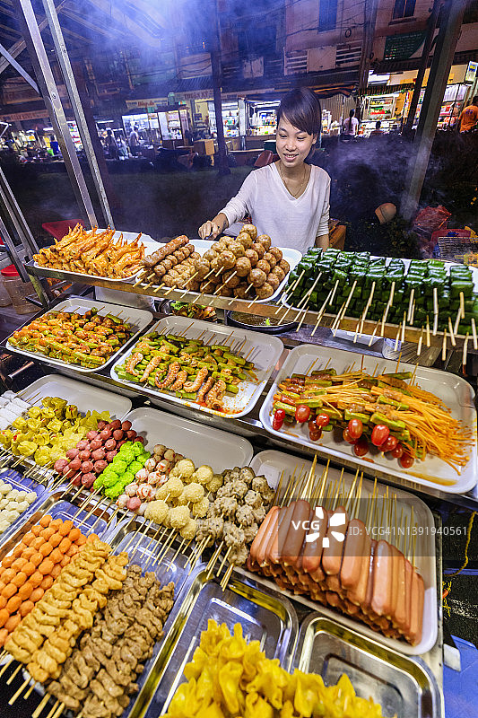 越南湄公河三角洲，一名越南男子在夜市上卖街头食物图片素材