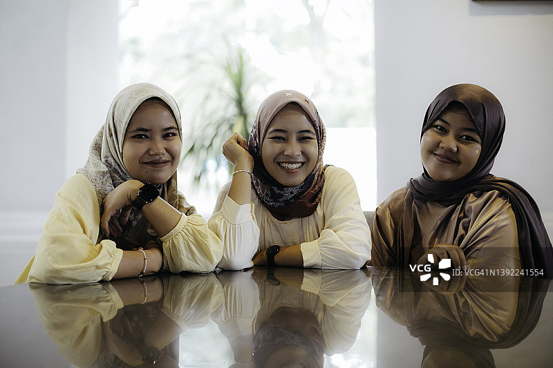 肖像微笑穆斯林妇女坐在一起图片素材