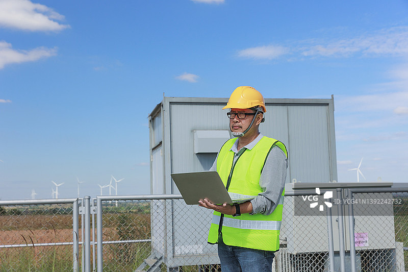 工程师可再生能源、清洁能源或环保理念的风力发电现场使用笔记本电脑。图片素材