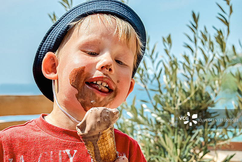 金发男孩喜欢吃巧克力冰淇淋弄脏自己图片素材