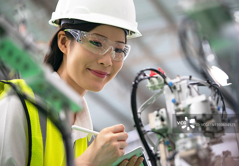 一幅工业女工程师双臂交叉站在工厂里的肖像图片素材