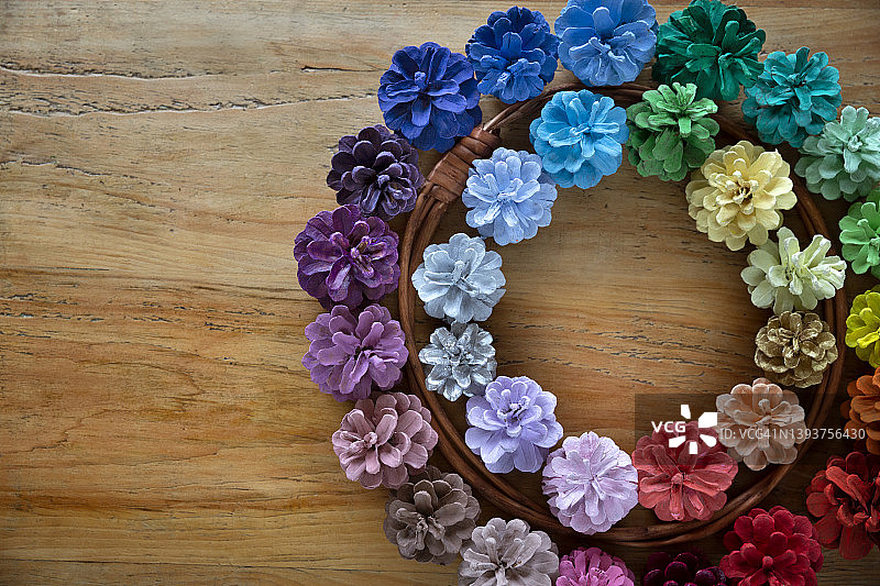 春天的花圈，由绘制了多种颜色的松果制成，放在木桌上，从上面直接拍摄。图片素材