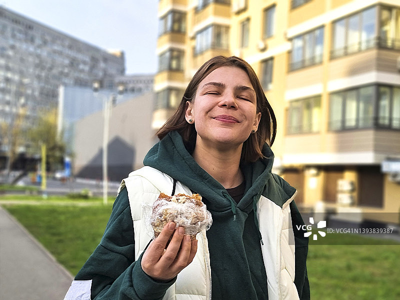 女人喜欢在城市街道上吃百吉饼图片素材