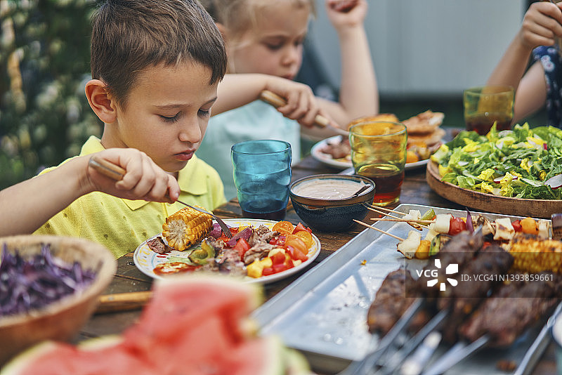 年轻的家庭吃羊肉，牛肉和蔬菜串蔬菜沙拉外面图片素材