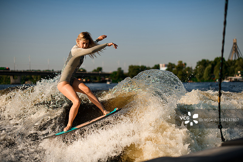 在温暖的日子里，女子娴熟地在飞溅的波浪上冲浪图片素材