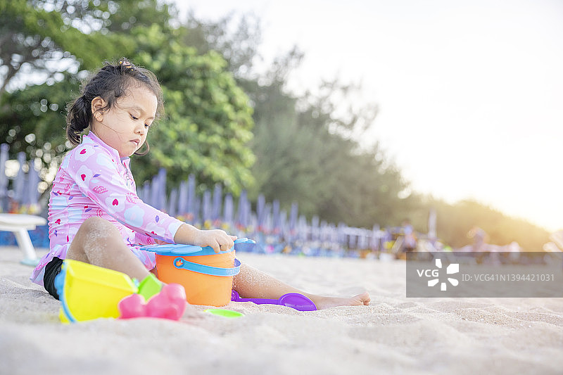 小女孩在沙滩上玩沙子，享受夏日图片素材
