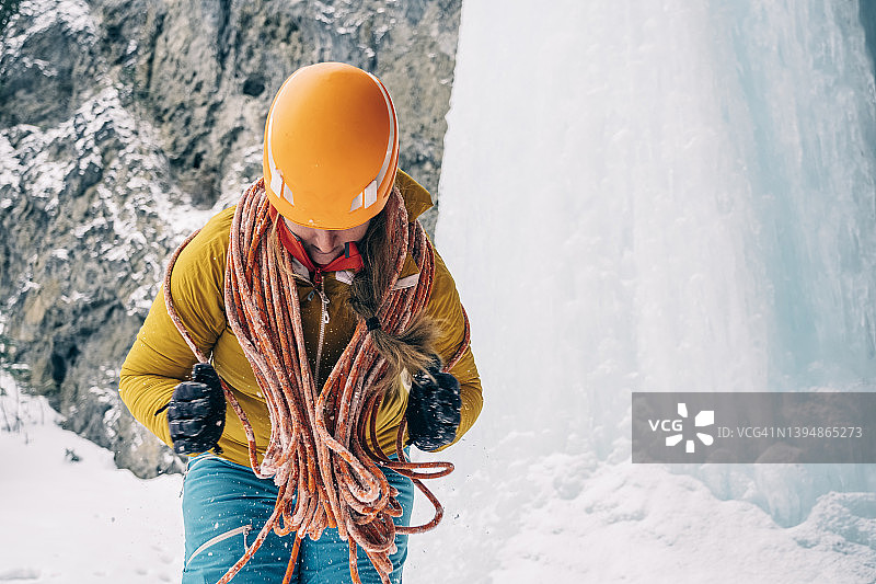 在班夫国家公园，一名女登山者在下雪时盘绕着一根攀冰绳图片素材