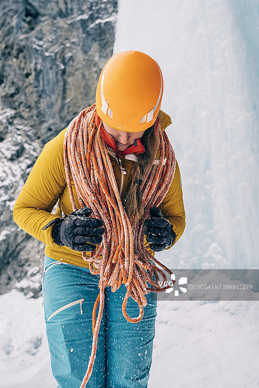 在班夫国家公园，一名女登山者在下雪时盘绕着一根攀冰绳图片素材