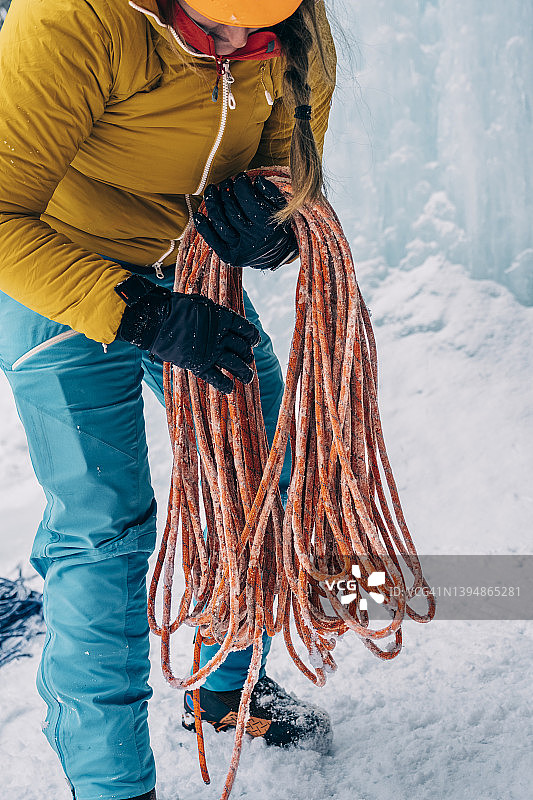 一名妇女在寒冷的山区环境中缠绕着一根登山绳图片素材